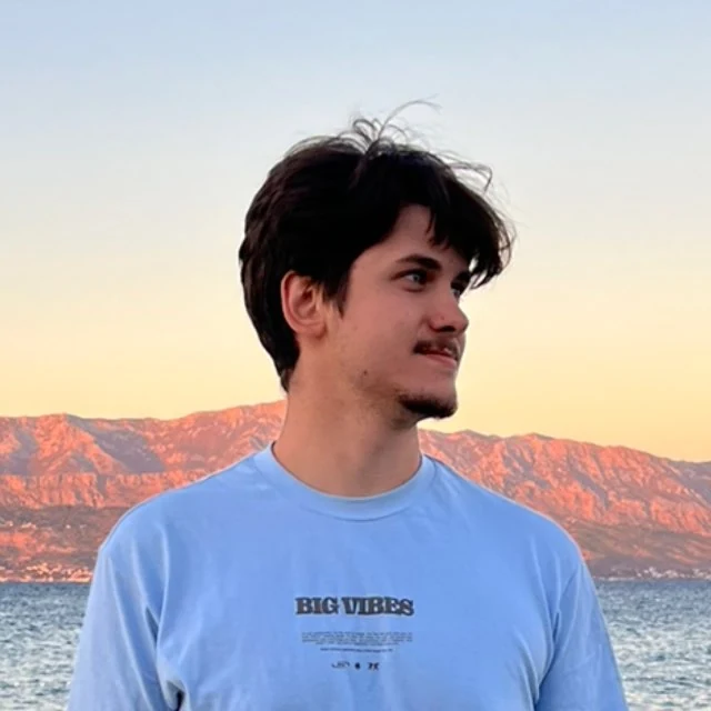 Denys Kovalenko at the coast, with mountains behind him